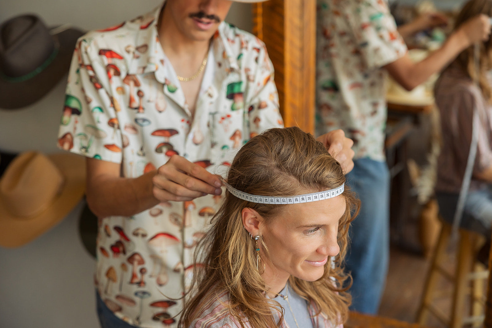 Person getting their head measured by another person in a casual setting for a western hat.