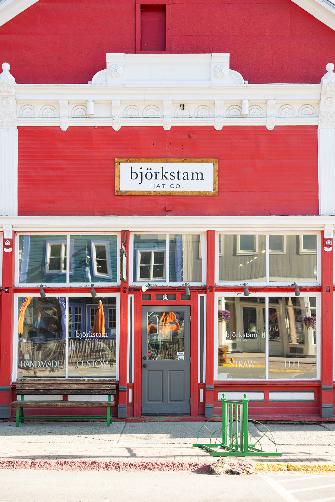 Red storefront with 'björkstam Hat Co' sign on a clear day