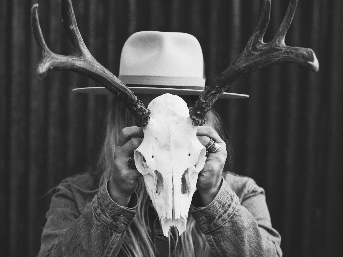 Elle in her Bjorkstam hat holding a deer skull with antlers.