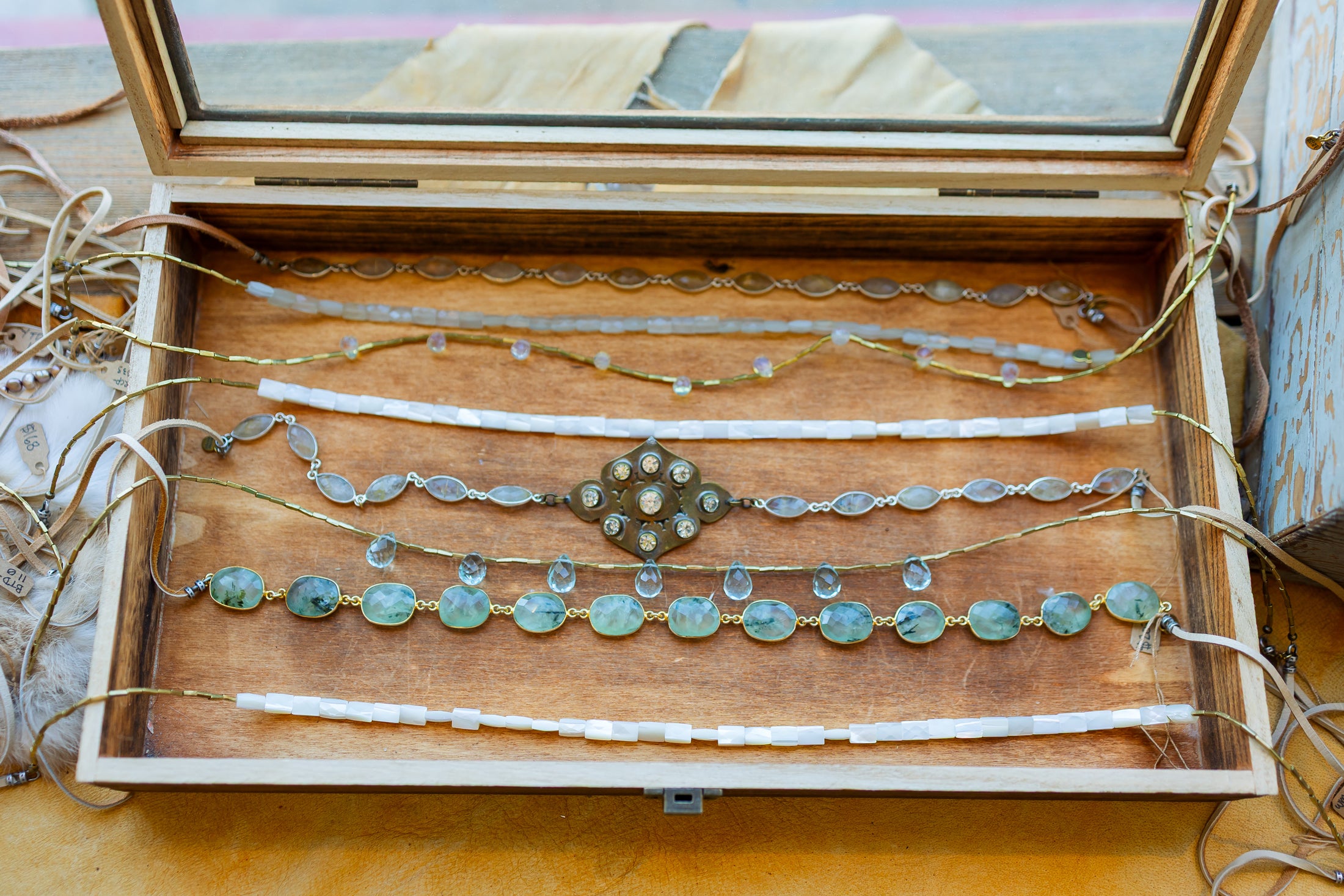 Wooden jewelry box with hat bands and necklaces on a wooden surface