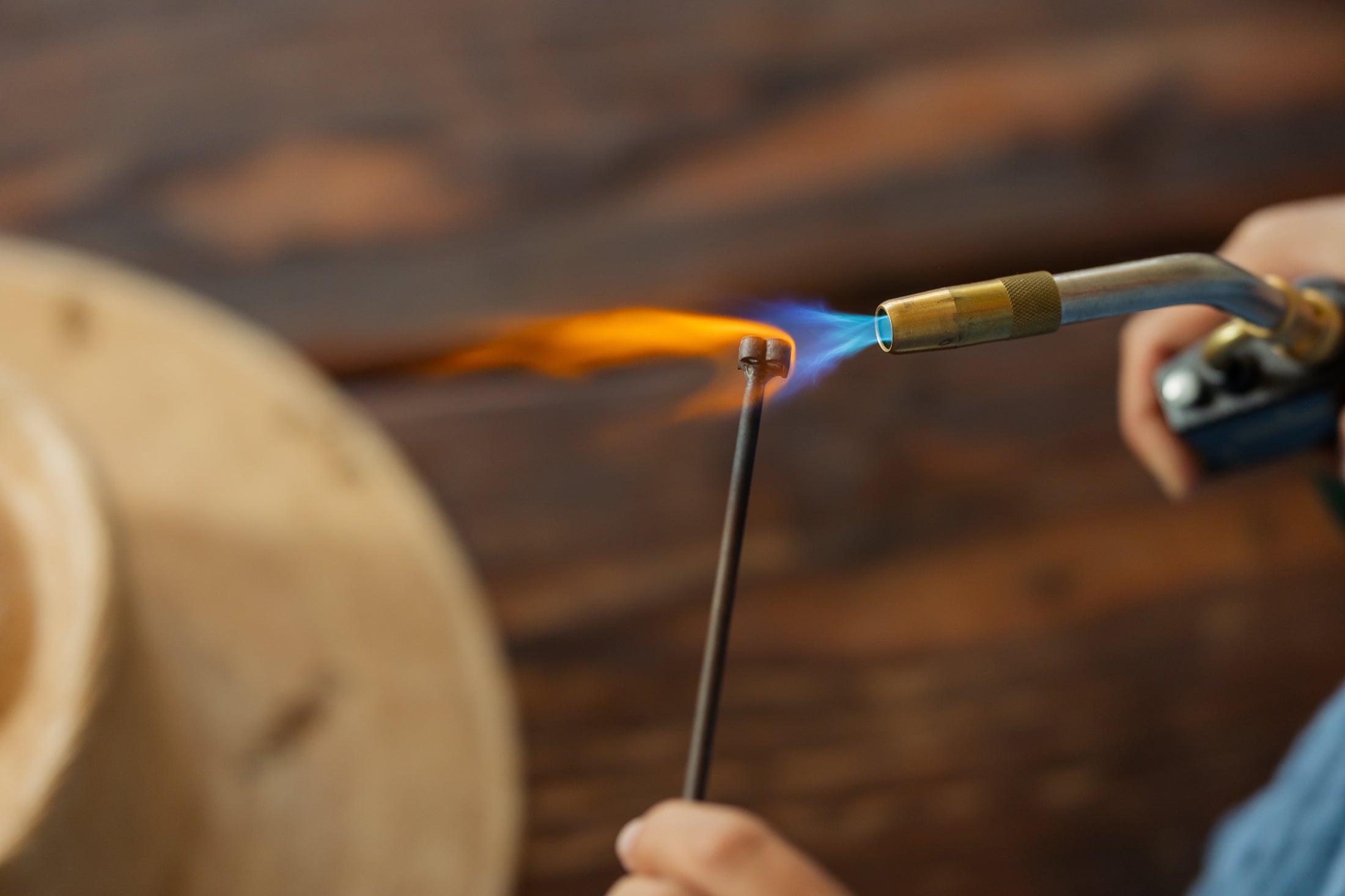Person using a torch to work with branding on hats on a wooden surface