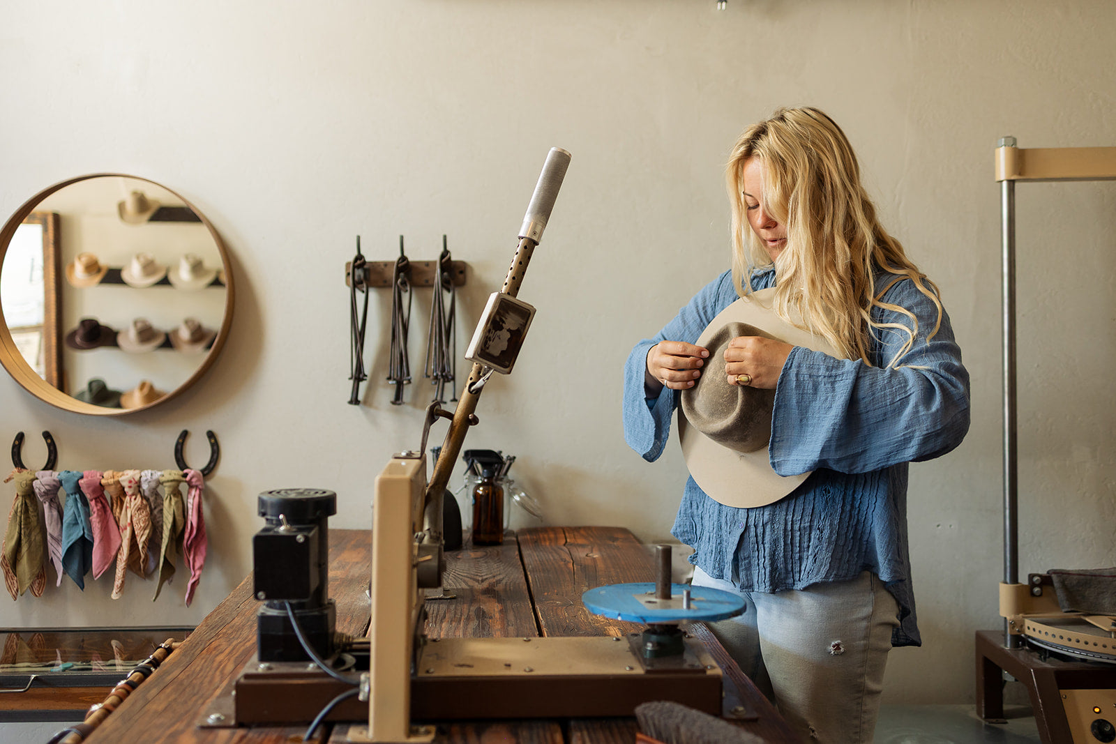 Person working with a tool in a hat workshop setting.