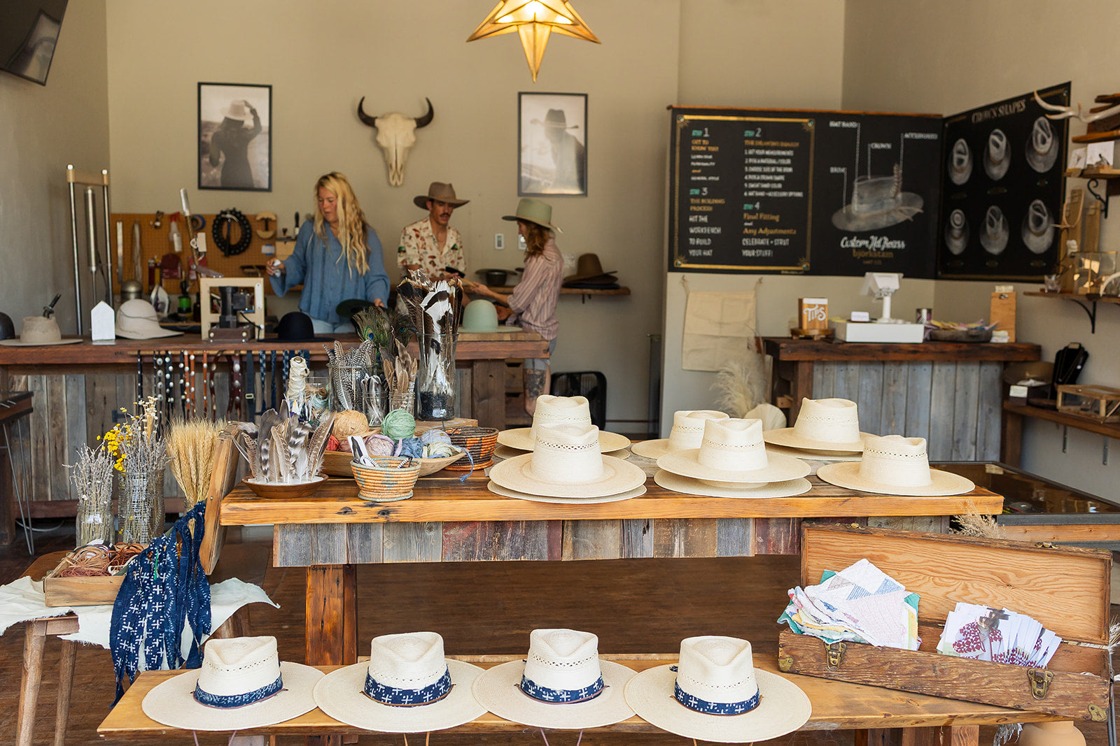 Display of cowboy hats on a table with a rustic interior setting.