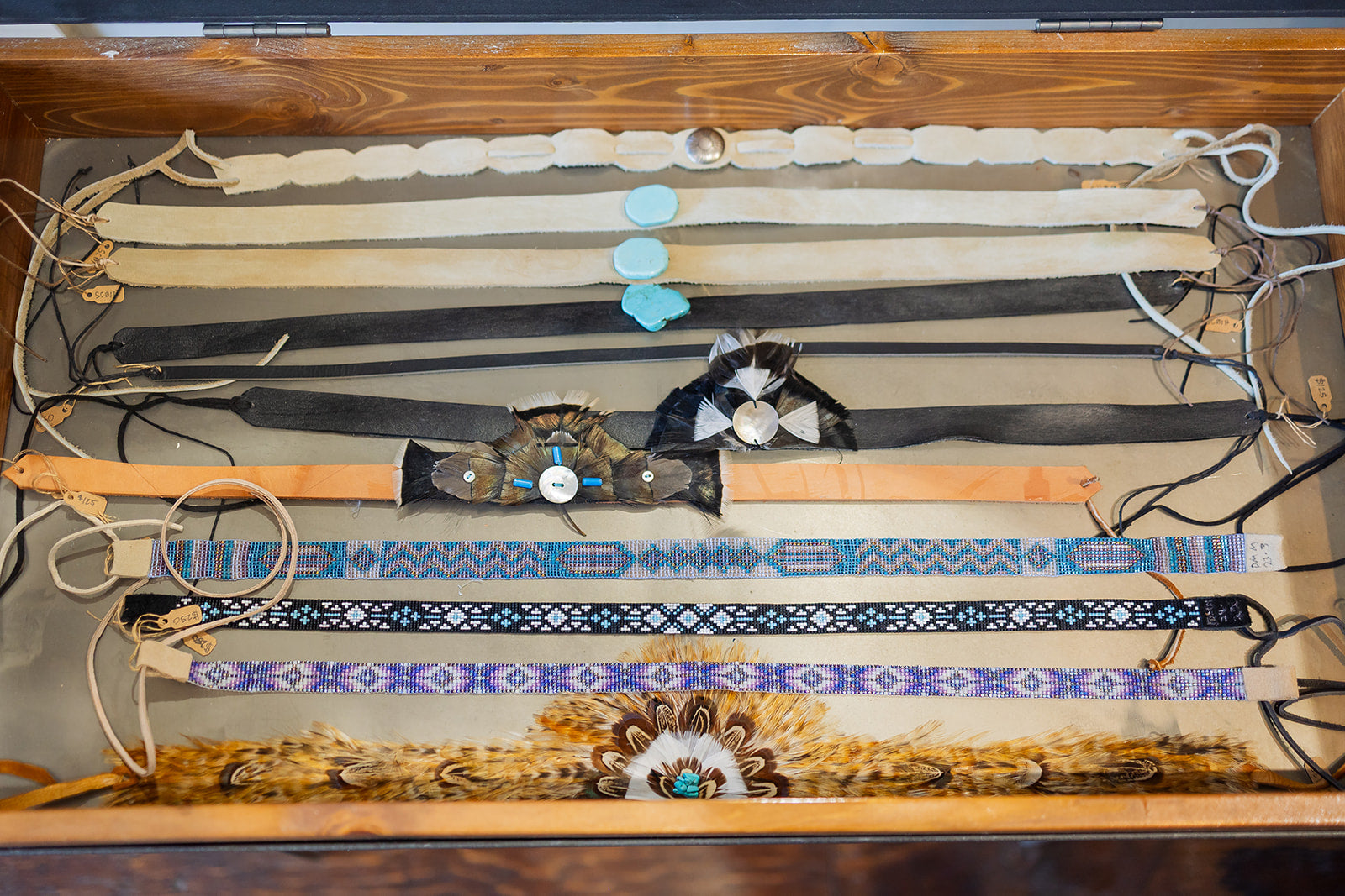 Collection of decorative hat bands displayed in a wooden case.