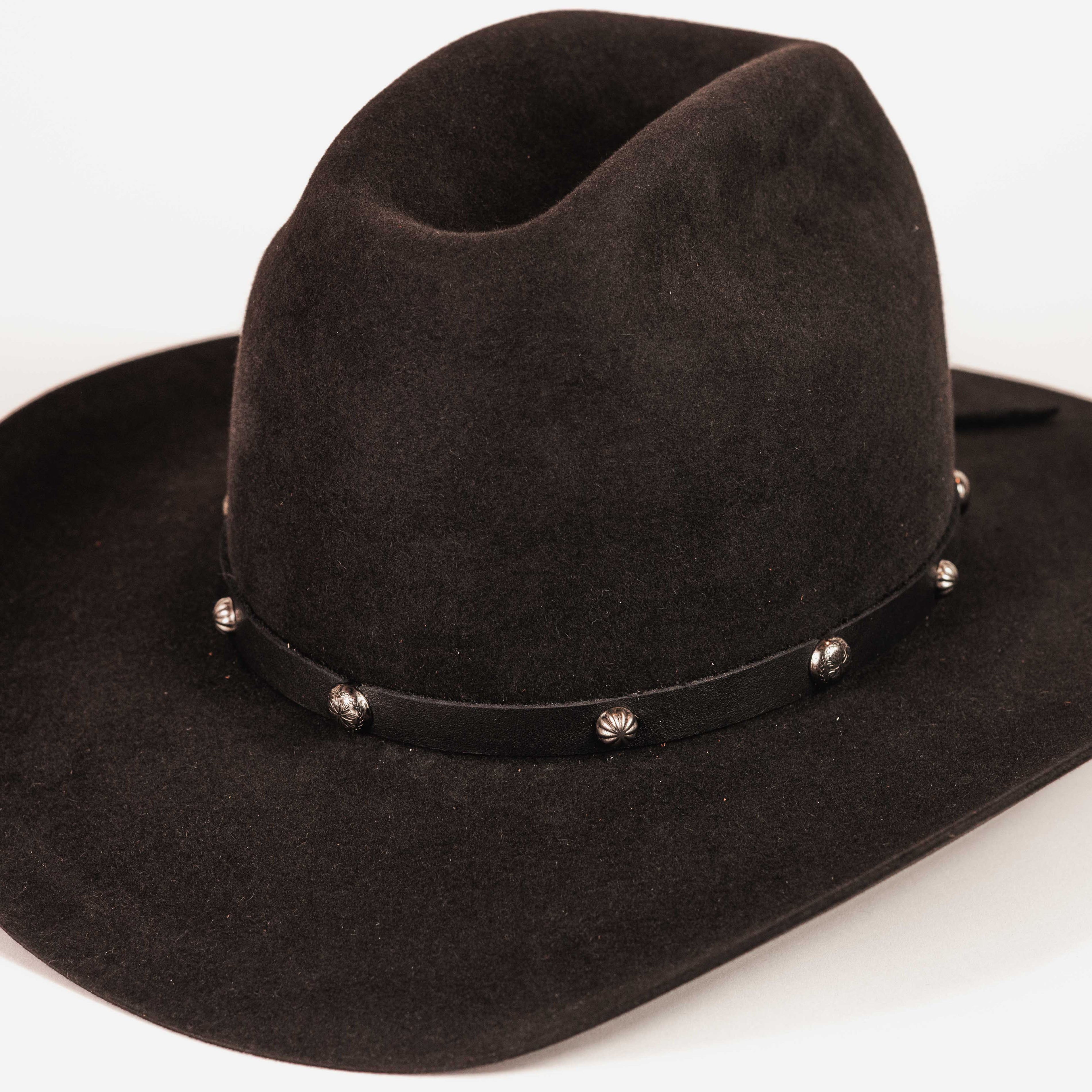 A black felt cowboy hat with a black leather band decorated with silver-toned metal studs, shown on a plain white background.