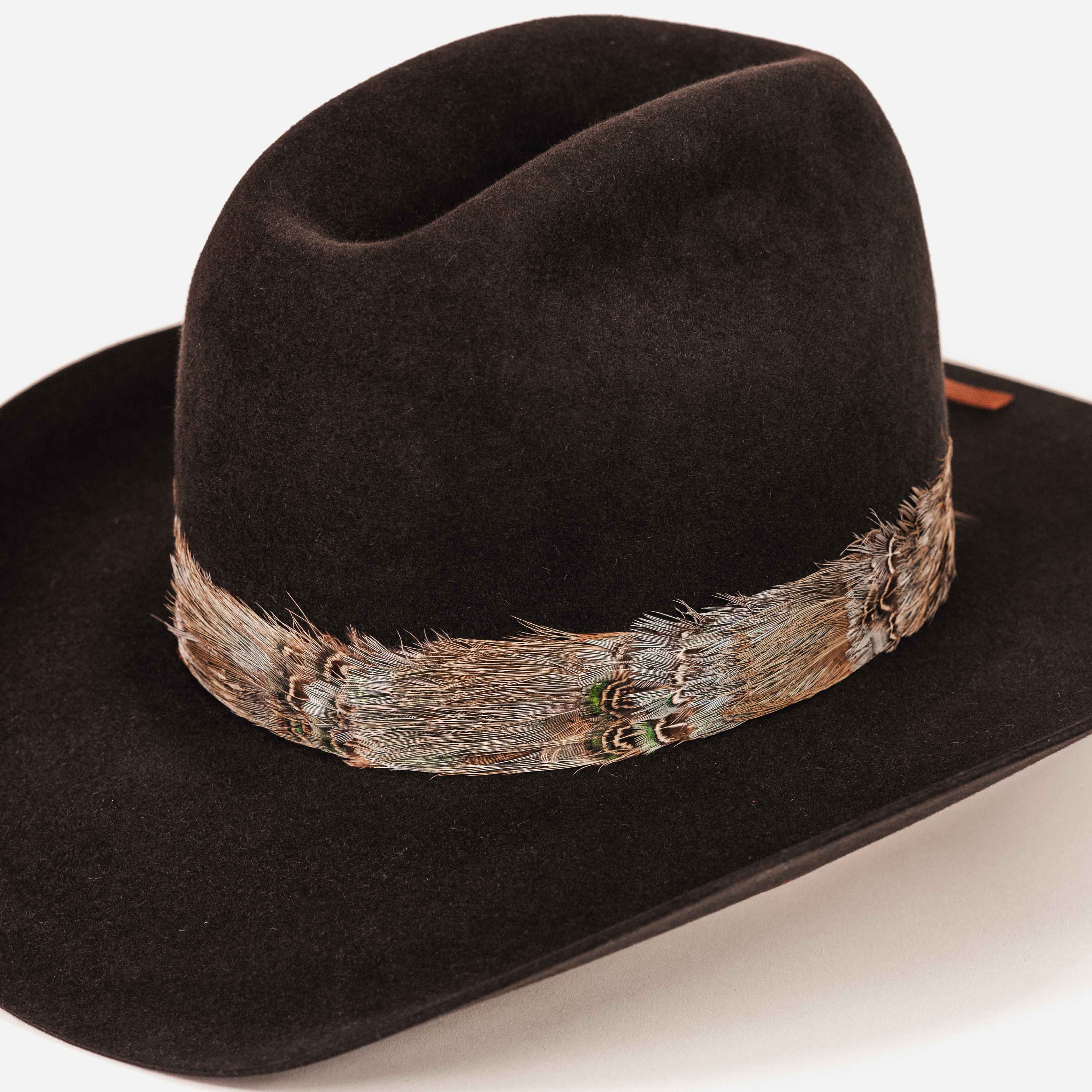 A black felt cowboy hat with a natural brown and gray feather band around the crown, photographed on a clean white background.