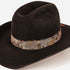 A black felt cowboy hat with a natural brown and gray feather band around the crown, photographed on a clean white background.
