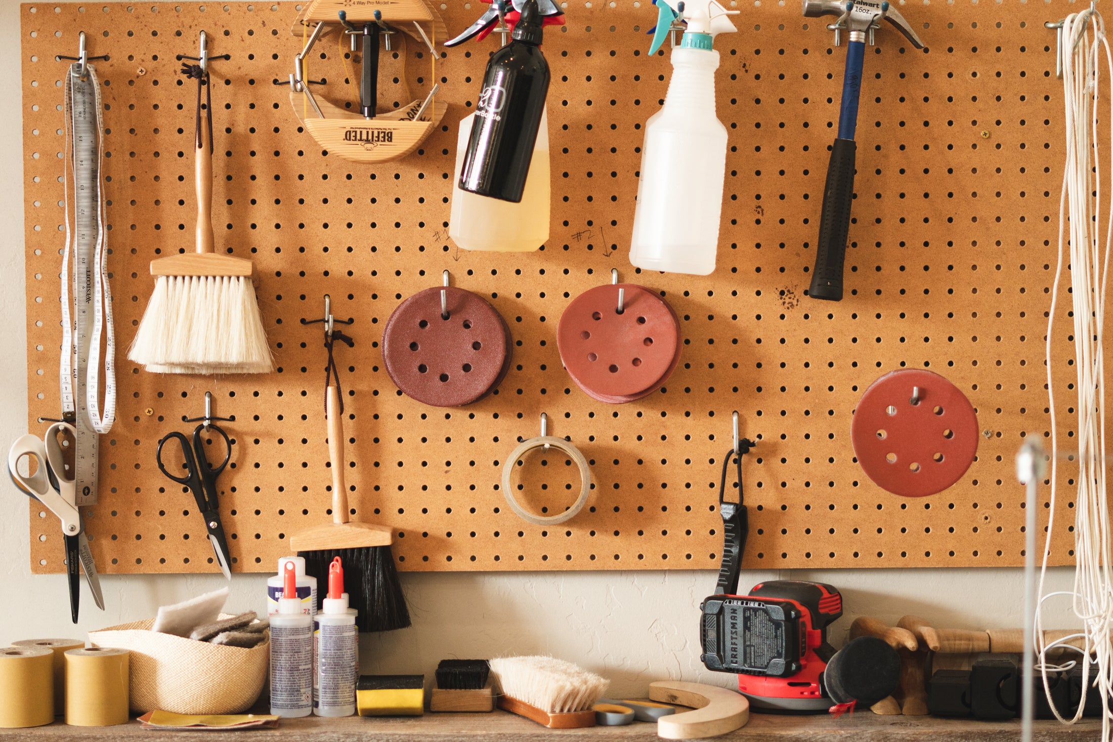 Pegboard with various tools and equipment hanging on it in a workshop setting.