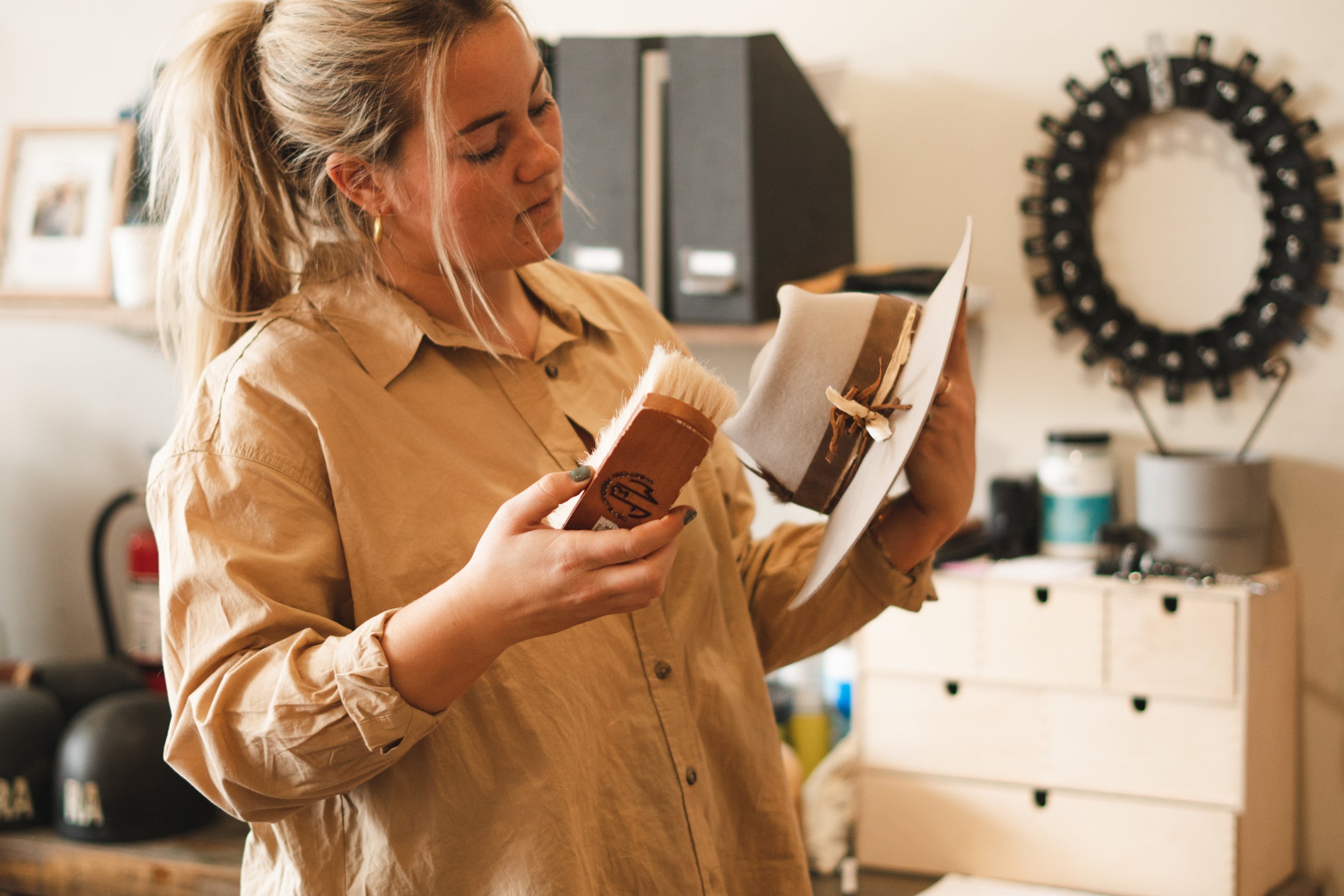 Elle holding a bjorkstam western hat and a horse hair brush.