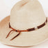 A light beige woven straw western hat with a brown leather band and silver-tone decorative studs, photographed on a clean white background.