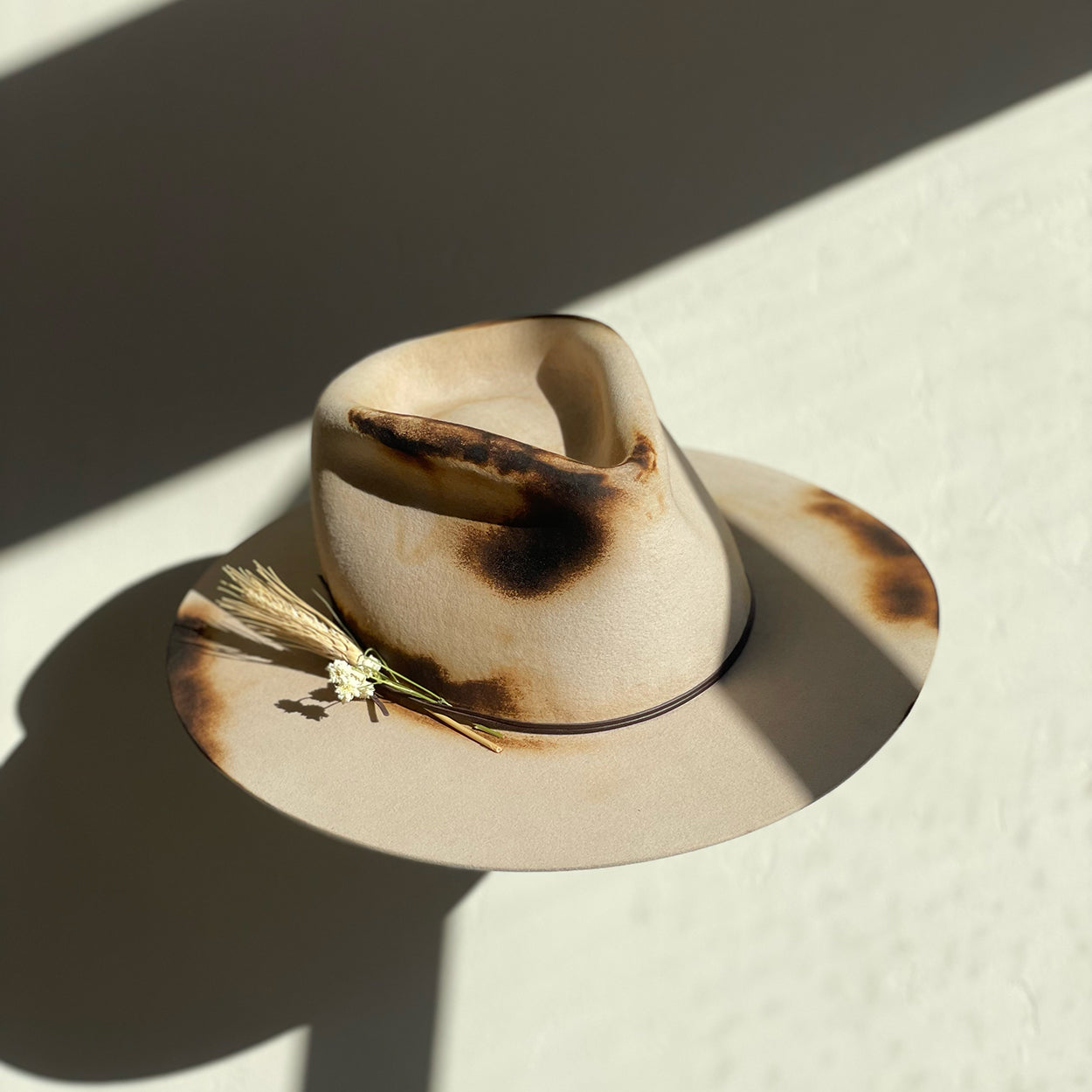 Beige hat with brown discoloration on a textured surface