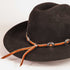 A dark brown felt cowboy hat with a brown leather band decorated with silver-toned concho-style hardware and orange-brown leather ties, shown on a plain light background.