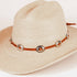 A light beige woven straw cowboy hat with a brown leather band decorated with silver-toned conchos and a small orange accent, shown on a plain light background.