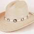 A light beige woven straw hat with a white band decorated with metallic silver conchos, shown on a plain light background.