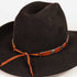 A black felt cowboy hat with a brown leather band and silver conchos, tied with a matching brown leather cord, shown against a plain white background.