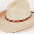 A light beige woven straw cowboy hat with a brown leather band and silver-toned square conchos, photographed on a clean white background.
